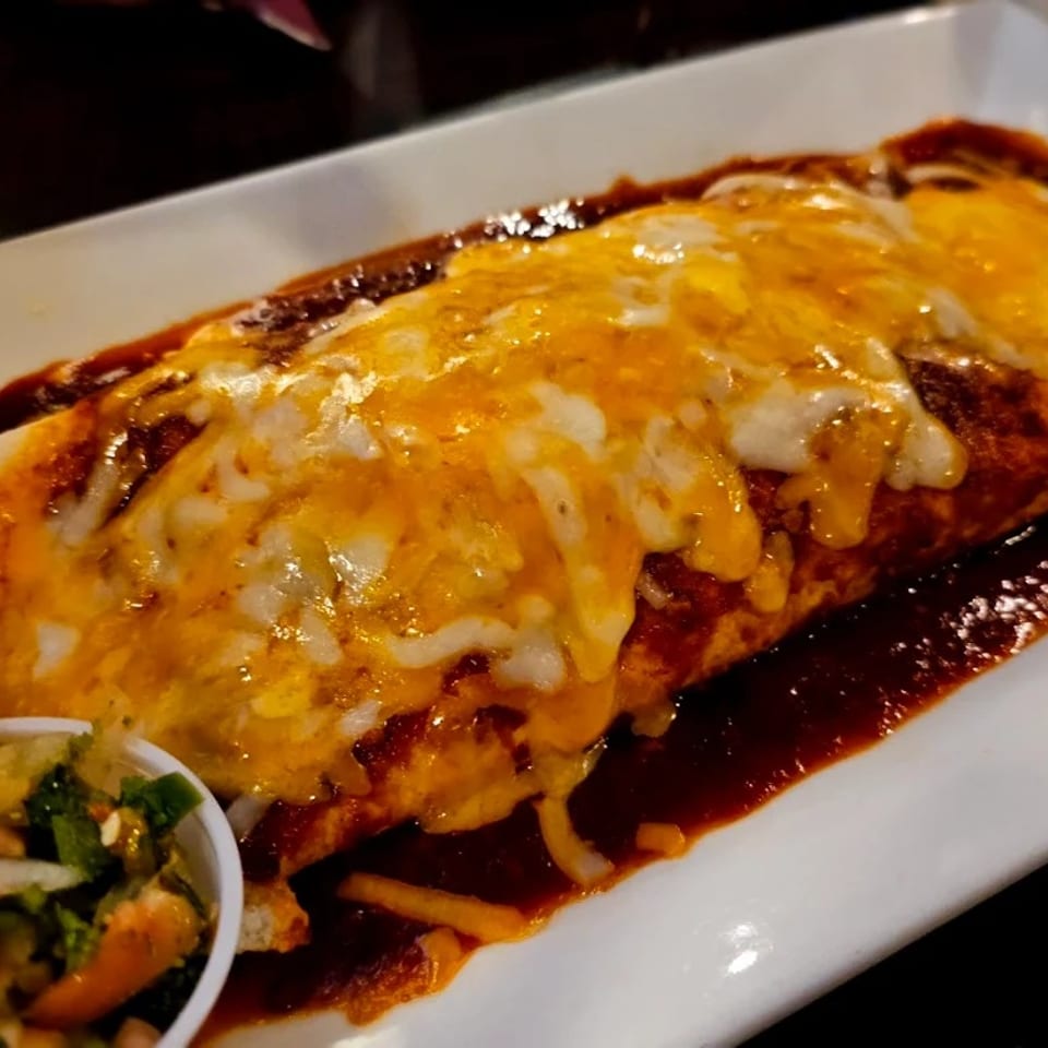 Supreme enchiladas covered with melted cheese and sauce.