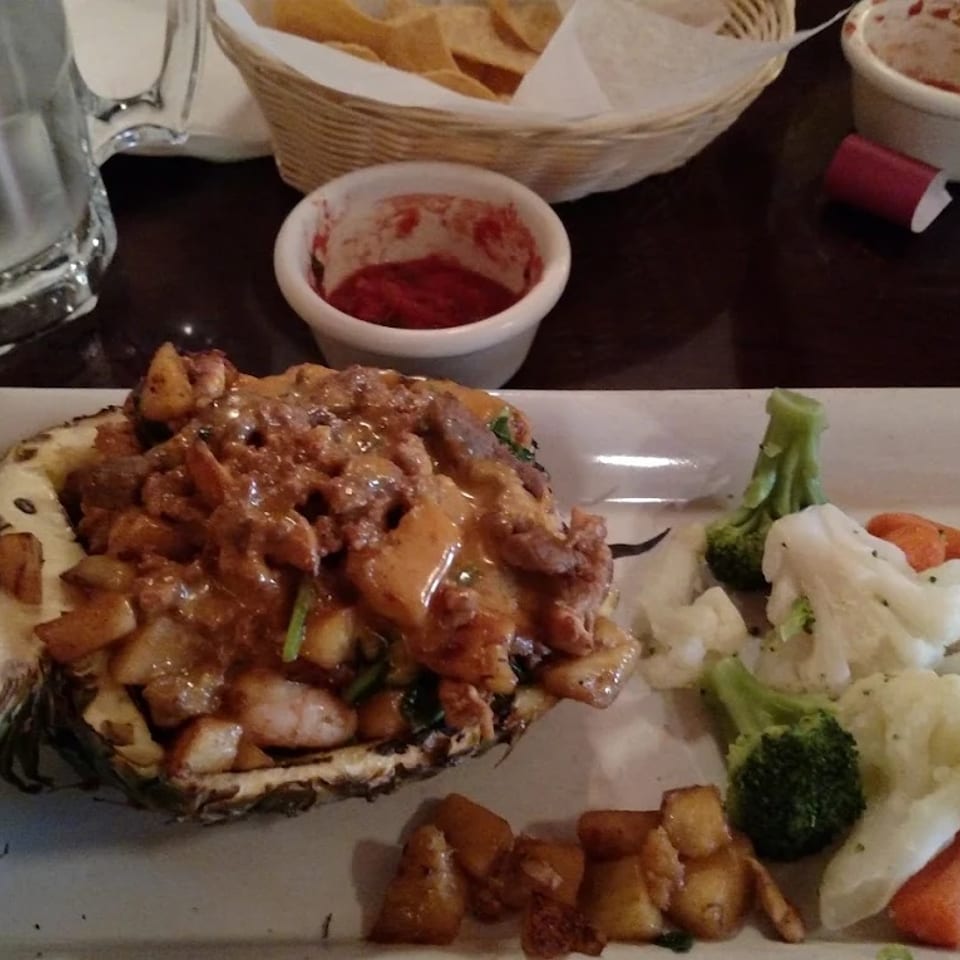 Pineapple fajitas served in a pineapple shell with vegetables.